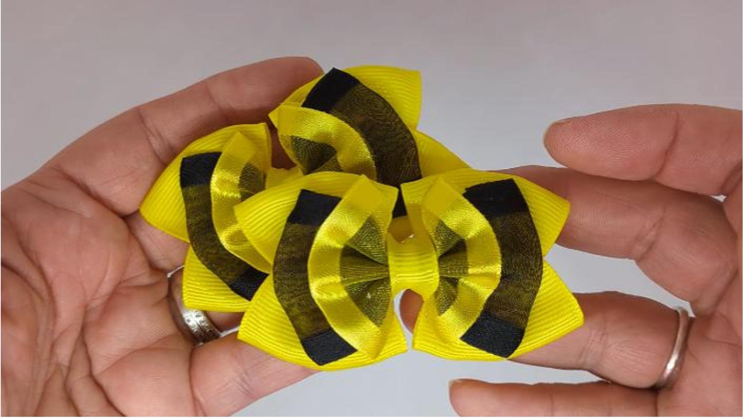 Close-up of yellow and black organza hair bows on alligator clips, measuring 7cm x 5cm, showcasing the vibrant colour contrast and delicate organza ribbon.