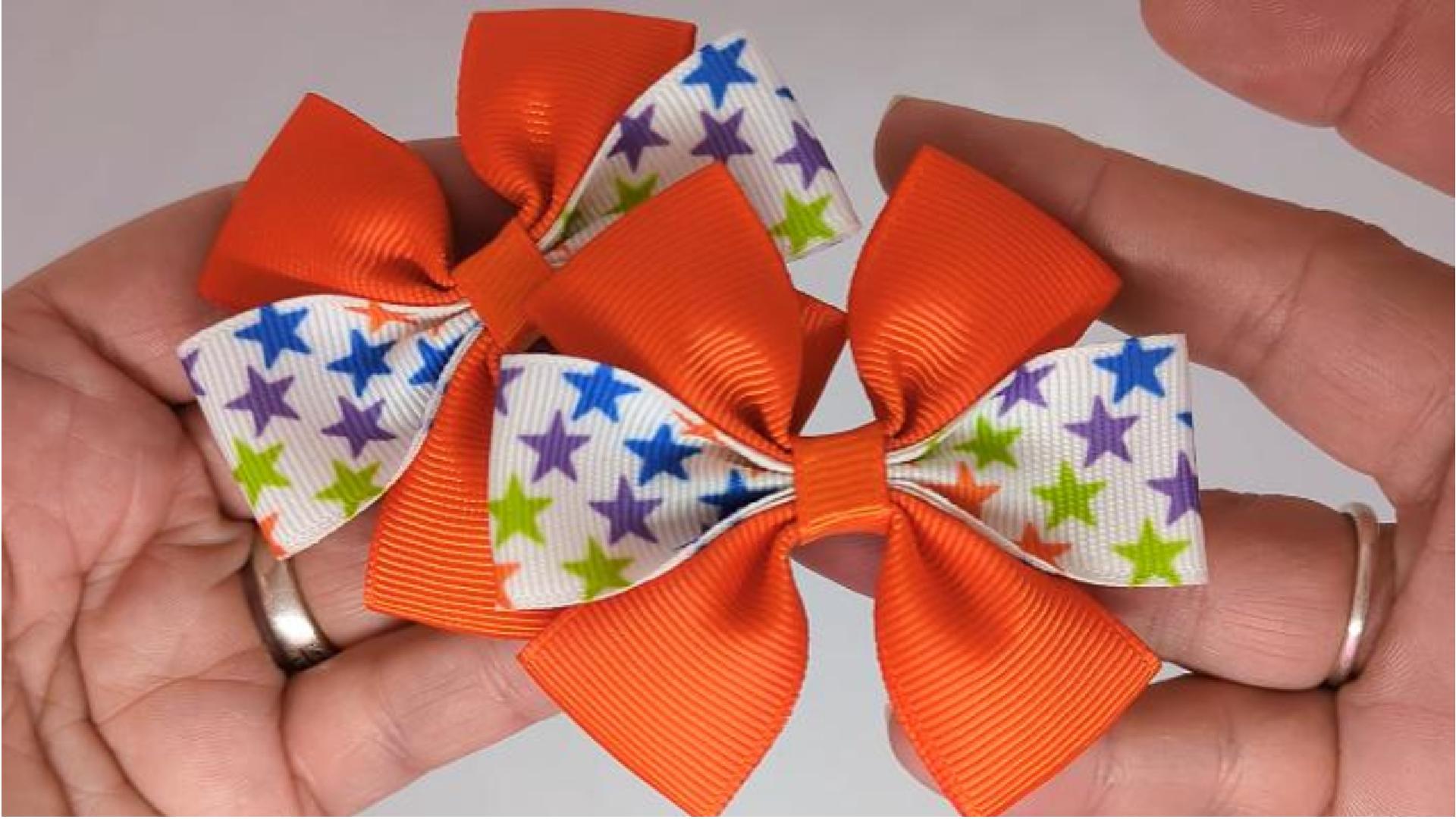 Close-up of orange and colourful stars hair bows on alligator clips, measuring 7cm x 5cm, showcasing the fun and vibrant stars design on the grosgrain ribbon.