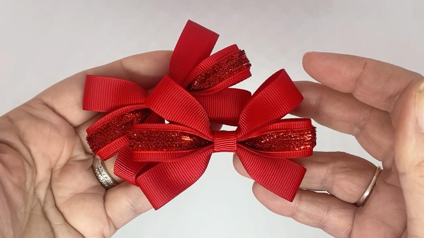 Close-up of red glitter hair bows on alligator clips, measuring 7cm x 5cm, showcasing the sparkle of the velvet glitter and grosgrain ribbon.