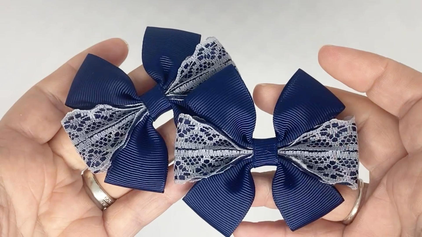 Close-up of navy blue and grey lace hair bows on alligator clips, measuring 7cm x 5cm, showcasing the delicate lace and grosgrain ribbon combination.