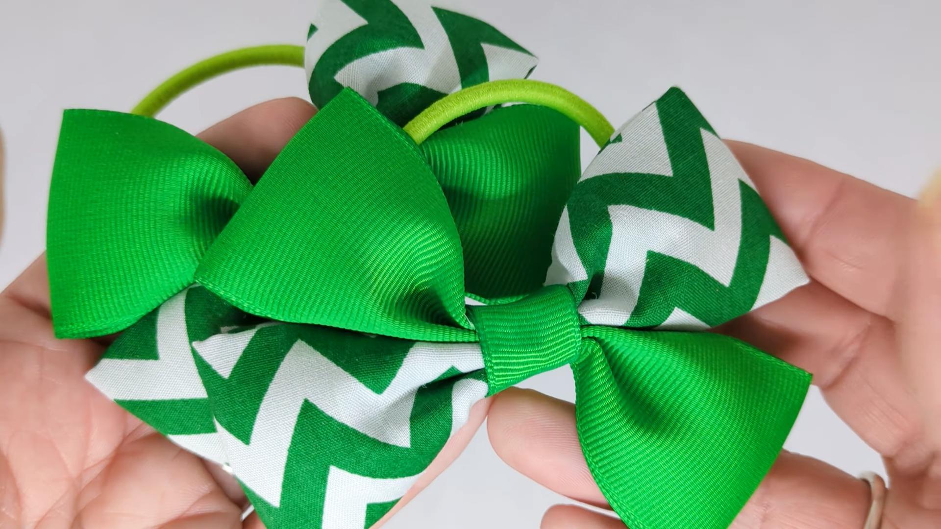 Close-up of emerald green chevron hair bows on thick bobbles, measuring 10cm x 7cm, showcasing the bold chevron pattern and grosgrain ribbon details.