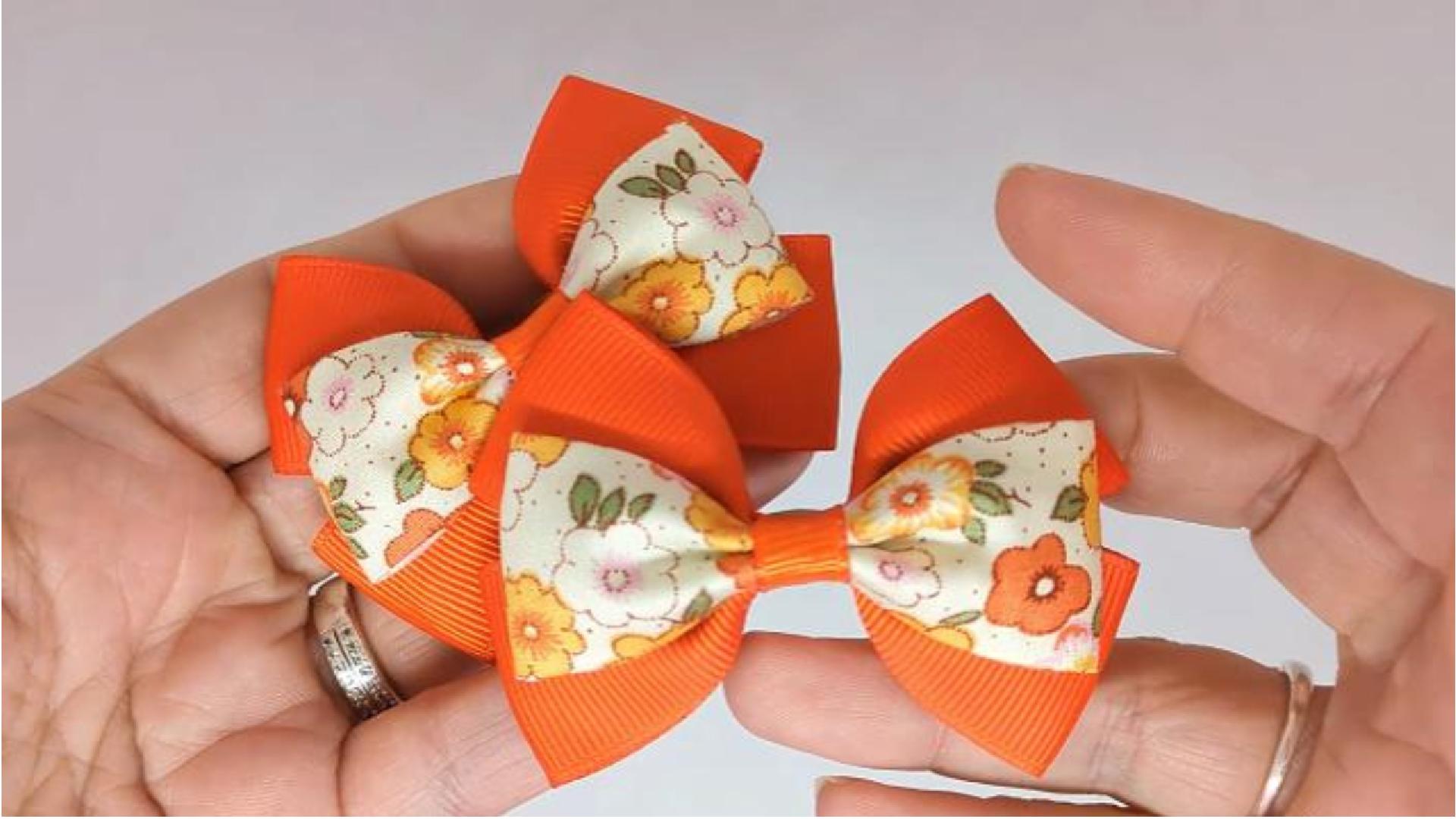 Close-up of orange and cream floral hair bows on alligator clips, measuring 7cm x 5cm, showcasing the combination of grosgrain ribbon and floral fabric design.