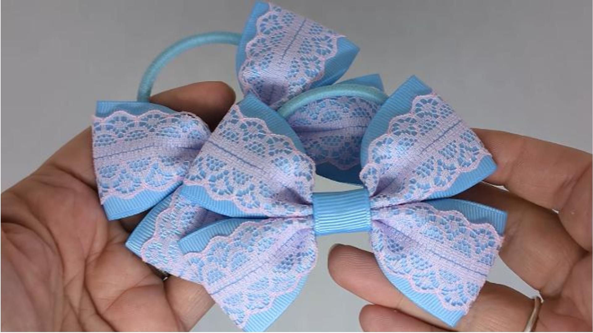 Close-up of baby blue and baby pink hair bows on thick bobbles, measuring 10cm x 7cm, showcasing the soft grosgrain and lace combination.