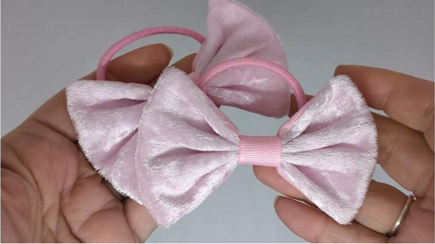 Close-up of pale pink velvet fabric hair bows on thick bobbles, measuring 9cm x 6cm, showcasing the soft texture of the velvet fabric.