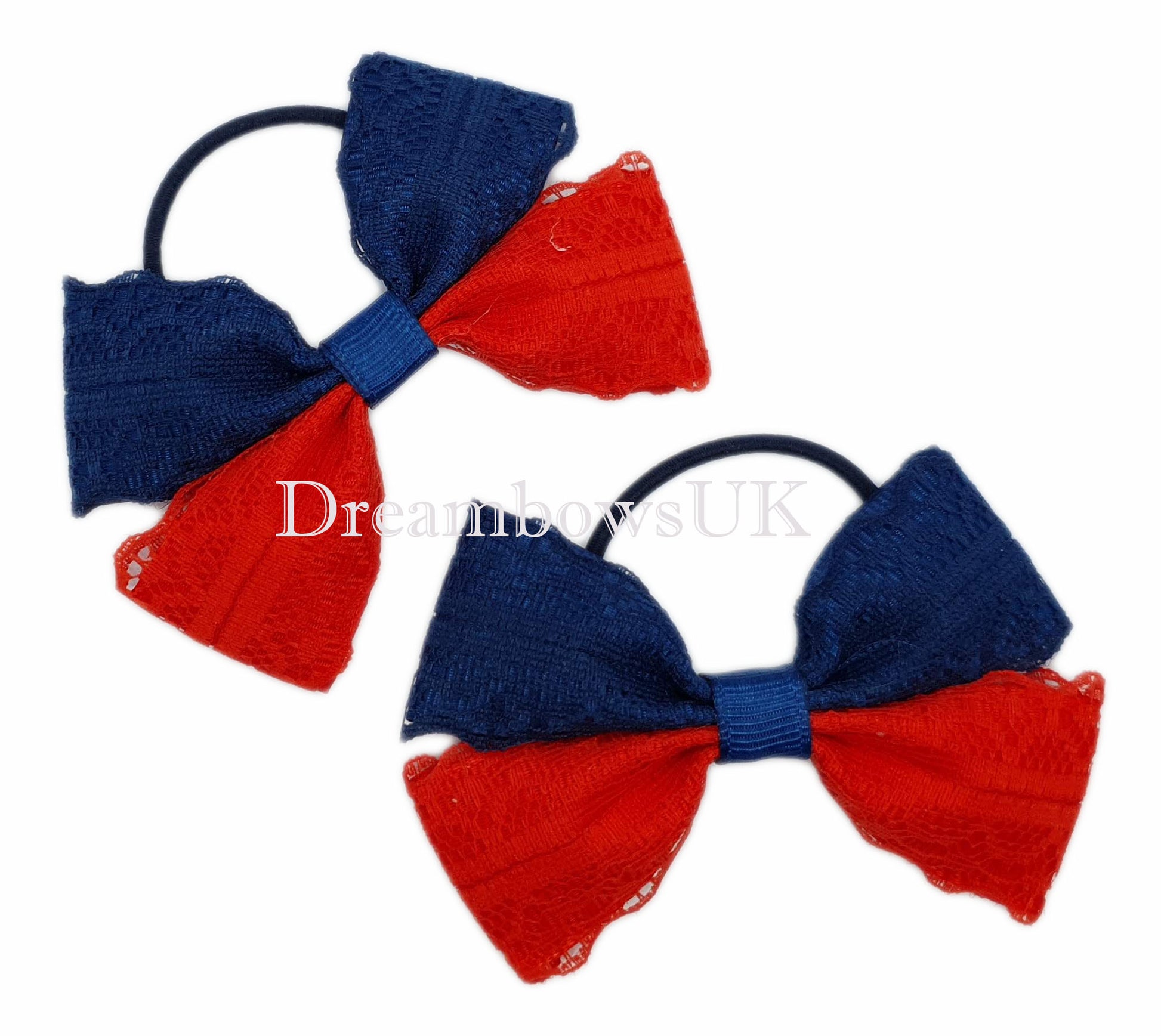 Navy blue and red hair bows attached to thin bobbles laying flat against a white background, showing the delicate lace design and contrasting colours of the ribbon.