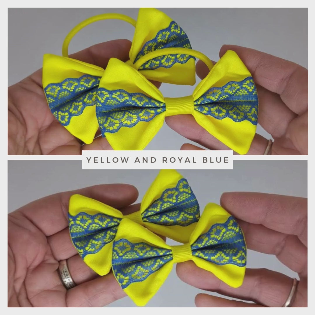 Close-up of yellow and royal blue hair bows on thick bobbles and alligator clips, showcasing the cotton fabric and lace combination.